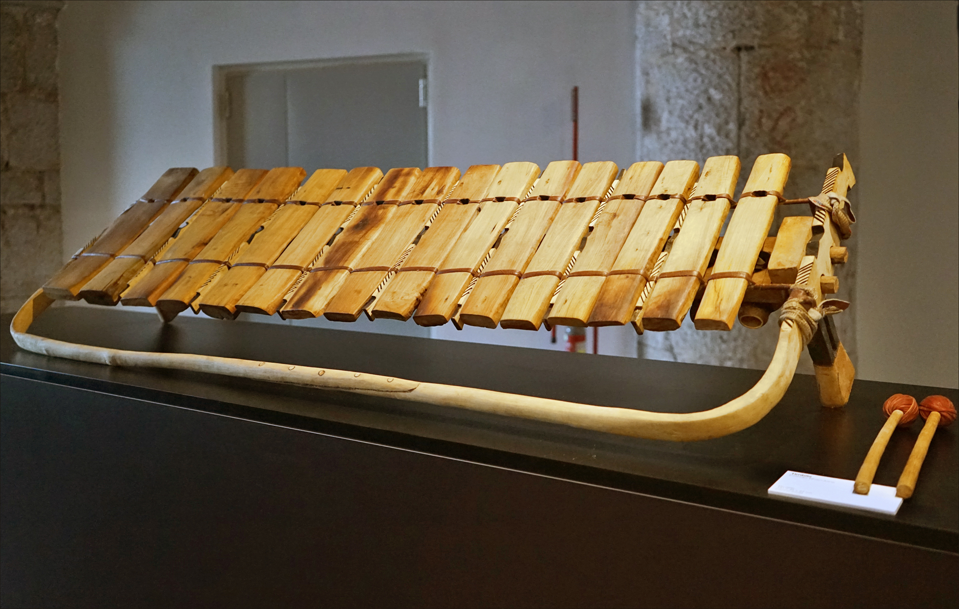 A Chopi timbila xylophone with wooden slat keys and gourd resonators, with two beaters