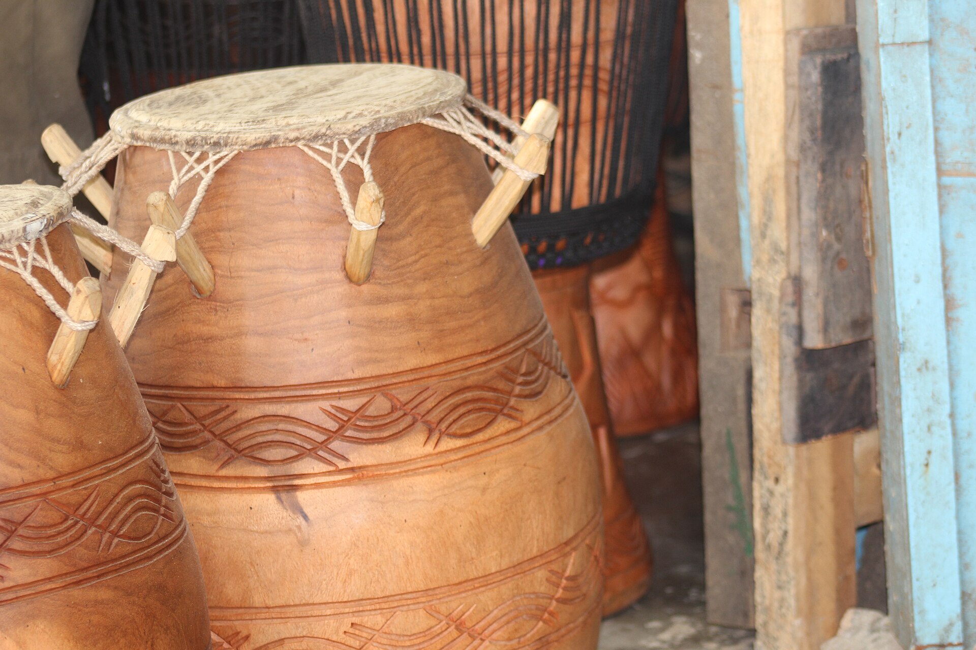 Carved and peg-tuned Ewe drums with decorated shells standing in a workshop
