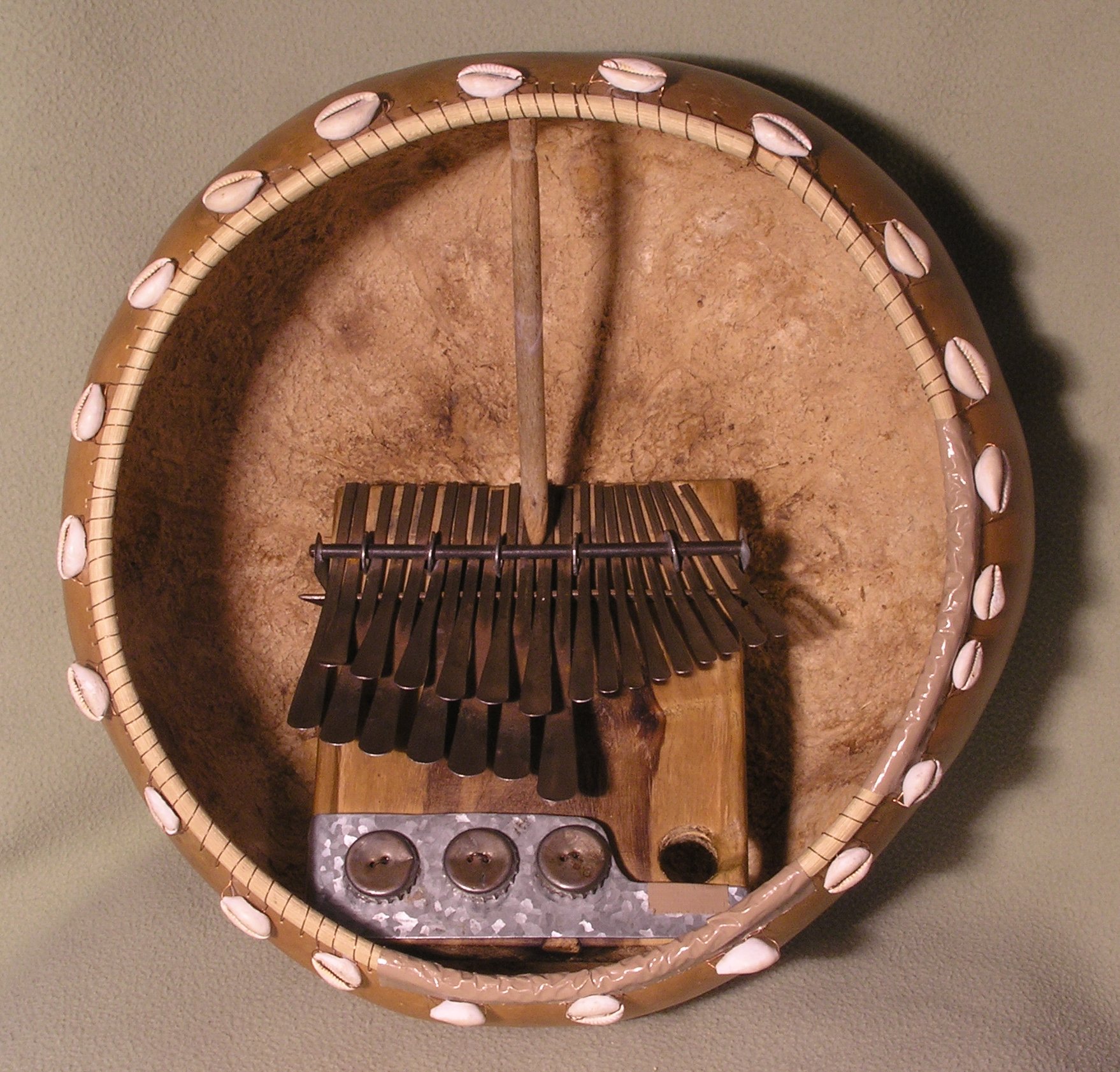 An mbira dzavadzimu seated inside a deze gourd resonator edged with cowrie shells
